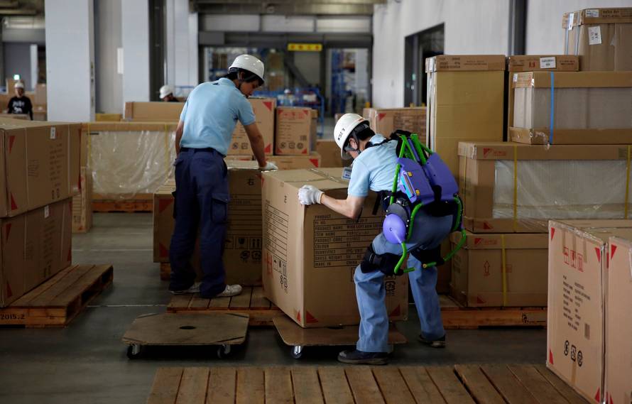 Okutani, 57, a contract worker of Ueda Co., Ltd., wears an Atoun Inc. Power Assist Suit, as he works at a distribution center in Kawasaki