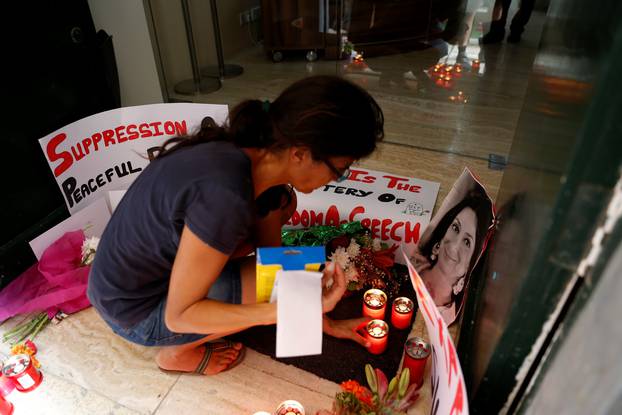 Activists place photos of assassinated anti-corruption journalist Caruana Galizia together with flowers, candles and protest posters, in the entrance of Malta
