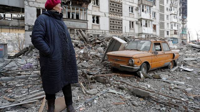 A local resident stands next to the building where her destroyed apartment is located in the besieged city of Mariupol