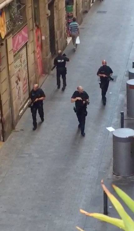 Armed police officers patrol an empty street after a van crashed into pedestrians near the Las Ramblas avenue in central Barcelona