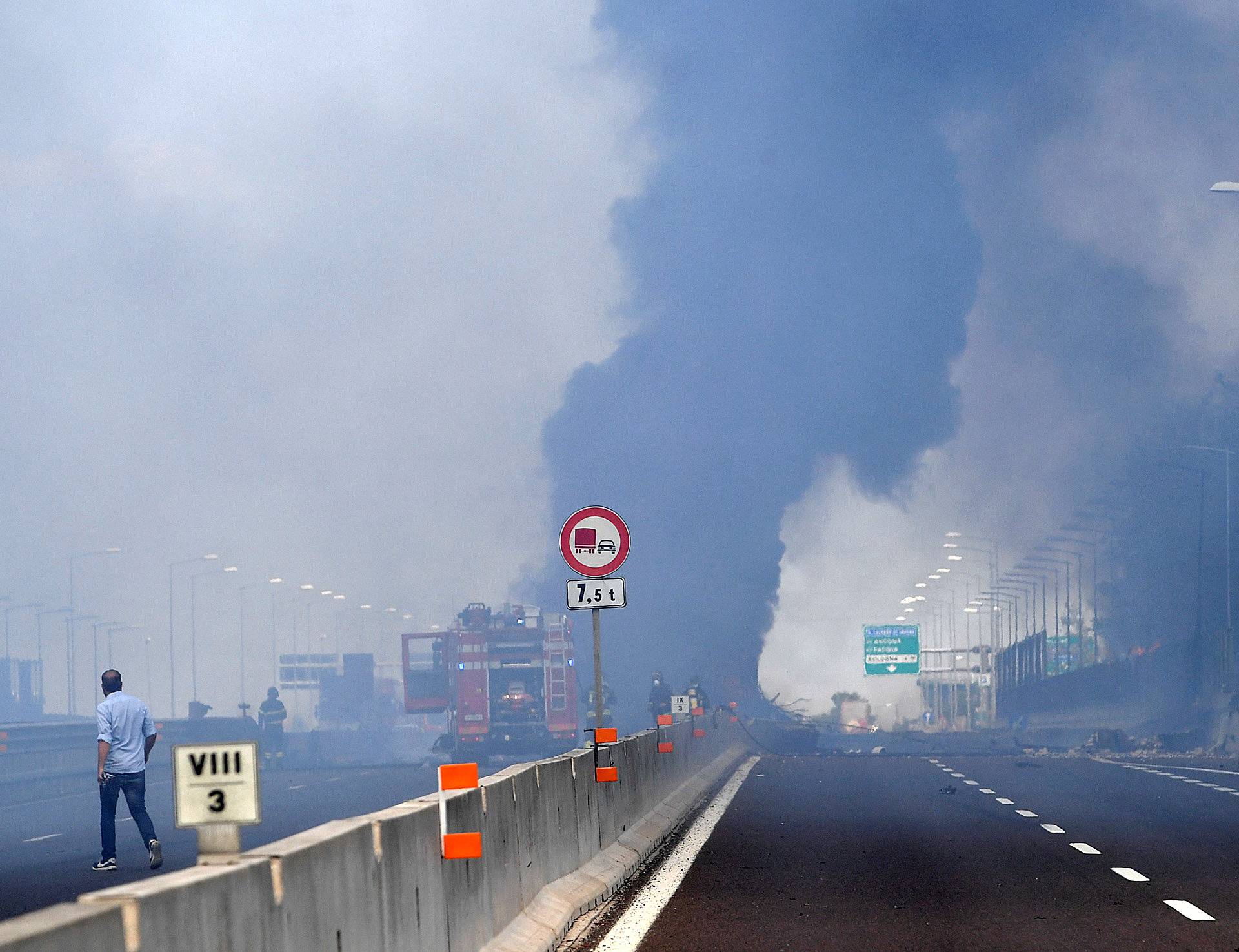 Firefighters work on the motorway after an accident caused a large explosion and fire at Borgo Panigale, on the outskirts of Bologna