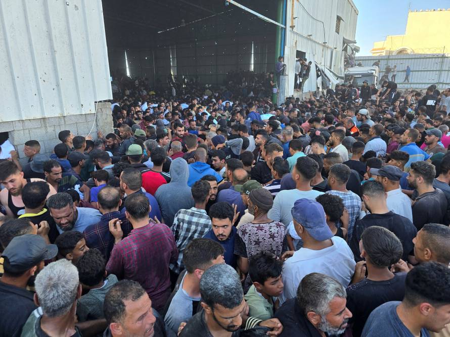 Palestinians gather at an aid distribution center in Deir Al-Balah, in the Gaza Strip