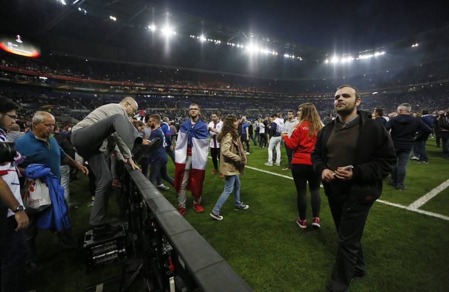Lyon fans on the pitch as fans clash in the stands
