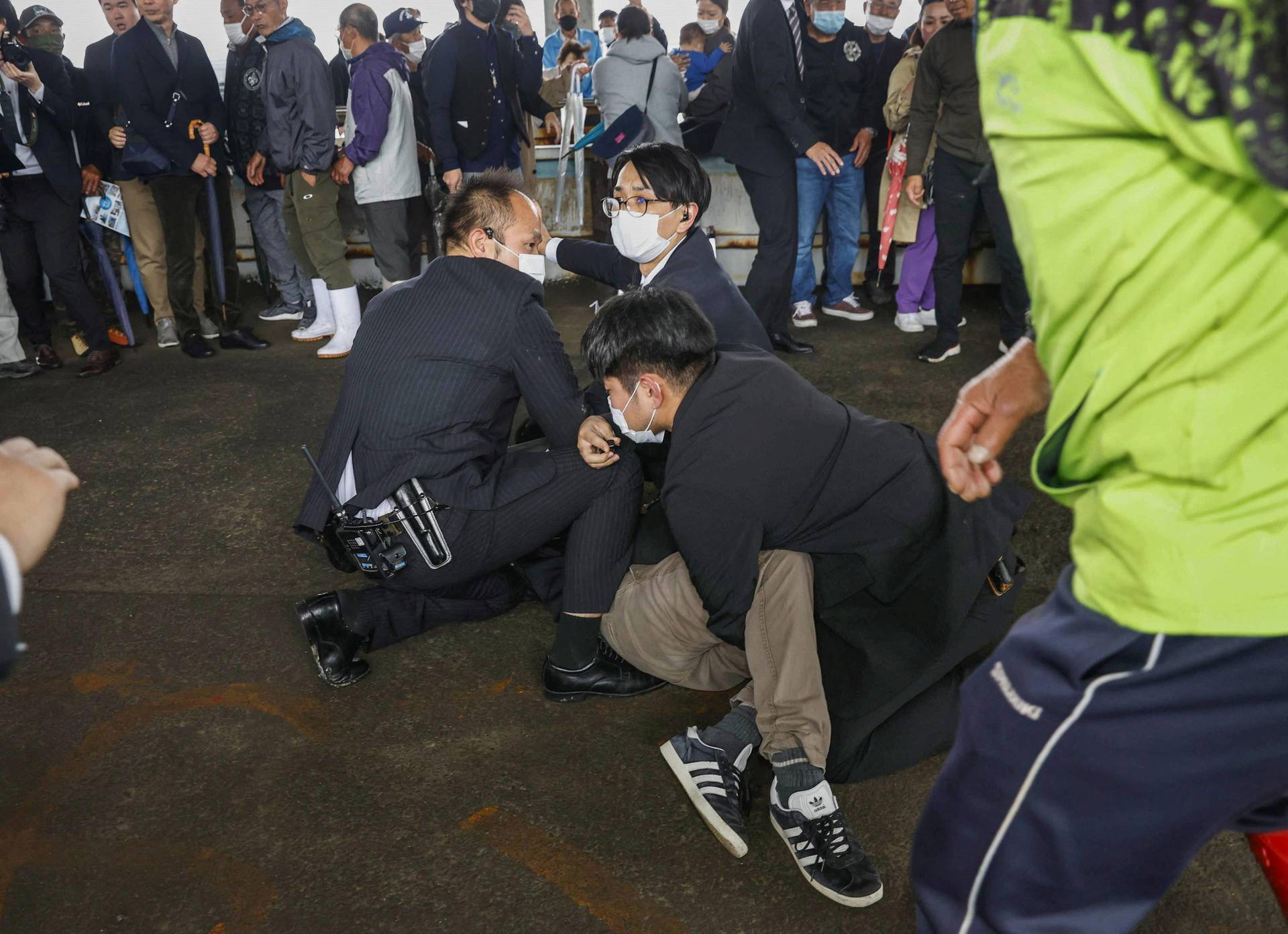 A man, believed to be a suspect who threw a pipe-like object near Japanese Prime Minister Fumio Kishida during his outdoor speech, is held by police officers in Wakayama