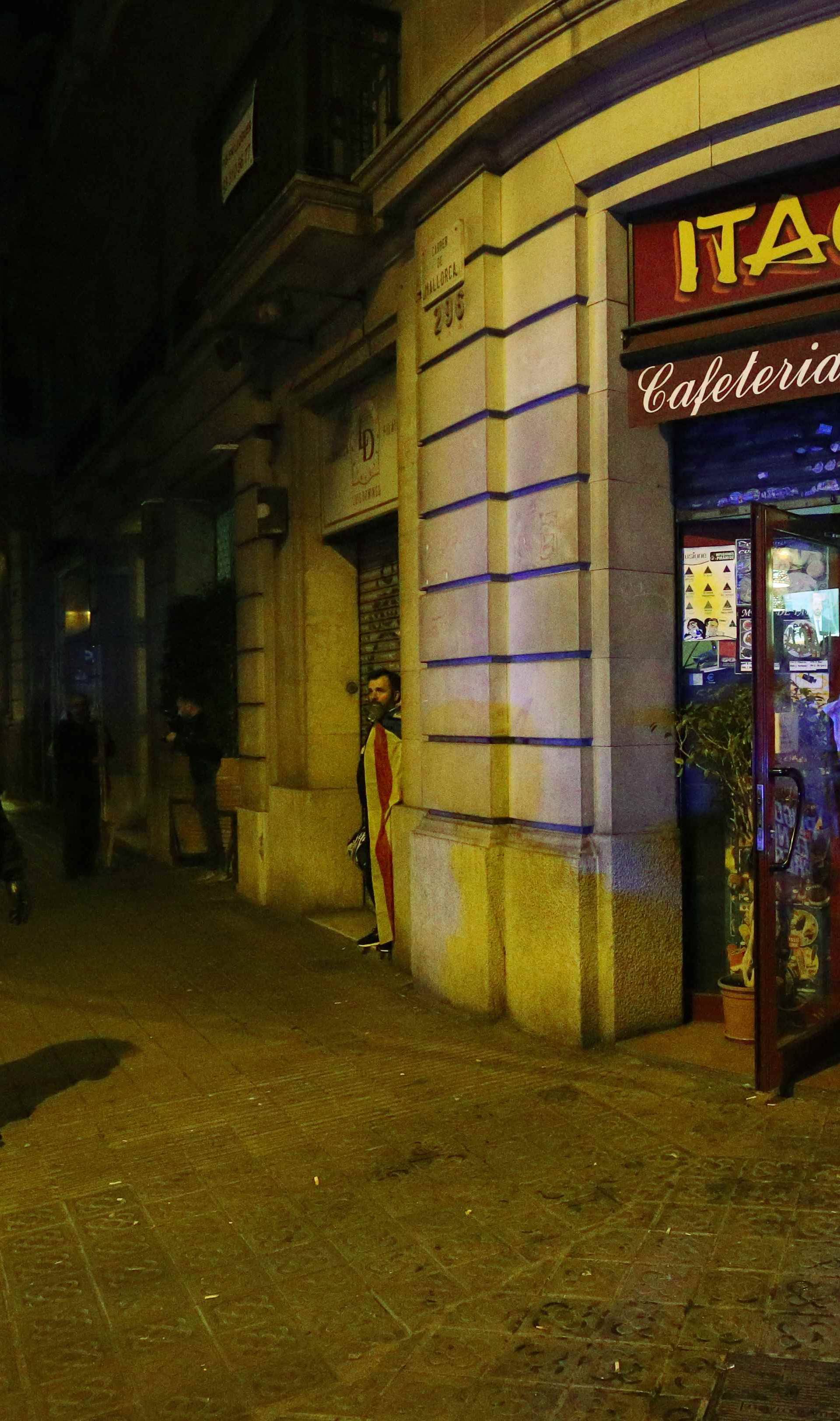 A protestor holds up a poster of former Catalan president Carles Puigdemont in the entrance of a cafe during skirmishes with police after Puigdemont was detained in Germany,  in Barcelona