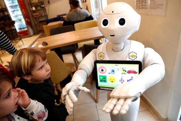 Children stand next to Pepper the robot at a cafe in Budapest