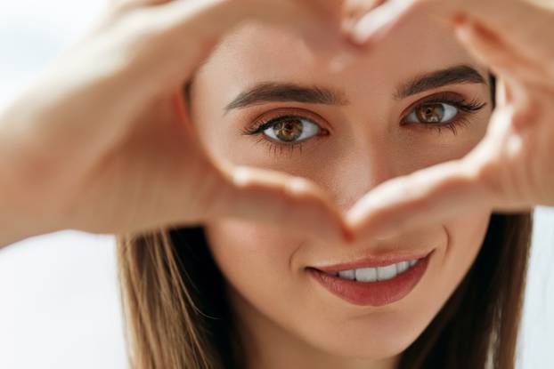 Beautiful Happy Woman Showing Love Sign Near Eyes.