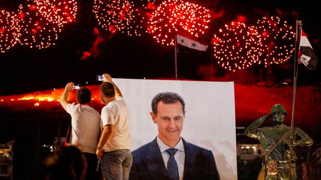 Supporters of Syria's President Bashar al-Assad celebrate after the results of the presidential election announced that he won a fourth term in office, in Damascus