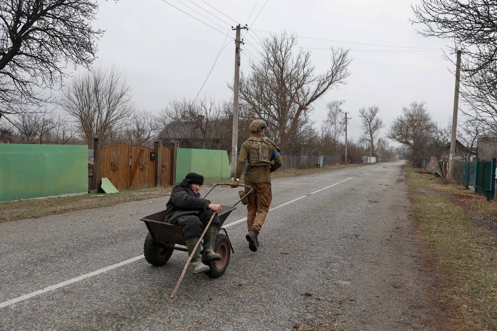 A Ukrainian service member evacuates the last local resident who stayed in a village near a frontline in Kyiv Region,