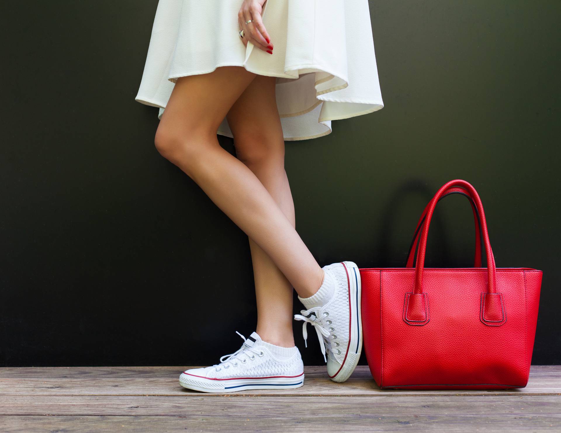 Beautiful fashionable big red handbag standing next to leggy woman