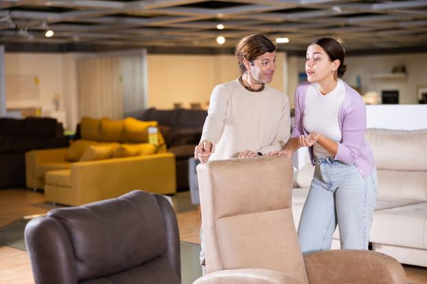 Man and woman looking to buy armchair in furniture store