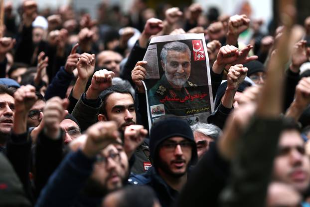 Iranians gesture as they gather to mourn General Qassem Soleimani in Tehran