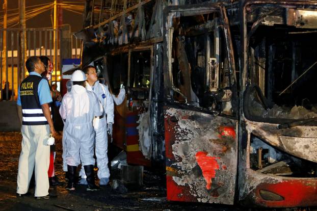 Peruvian police and investigators work next to a burnt bus on a street in Lima