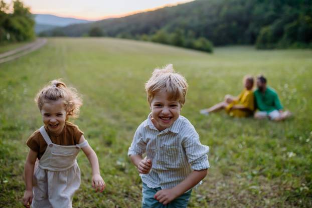 Happy young family spending time together outside in green nature.