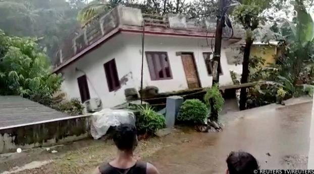 People watch a house being washed away in river due to strong current in Kottayam
