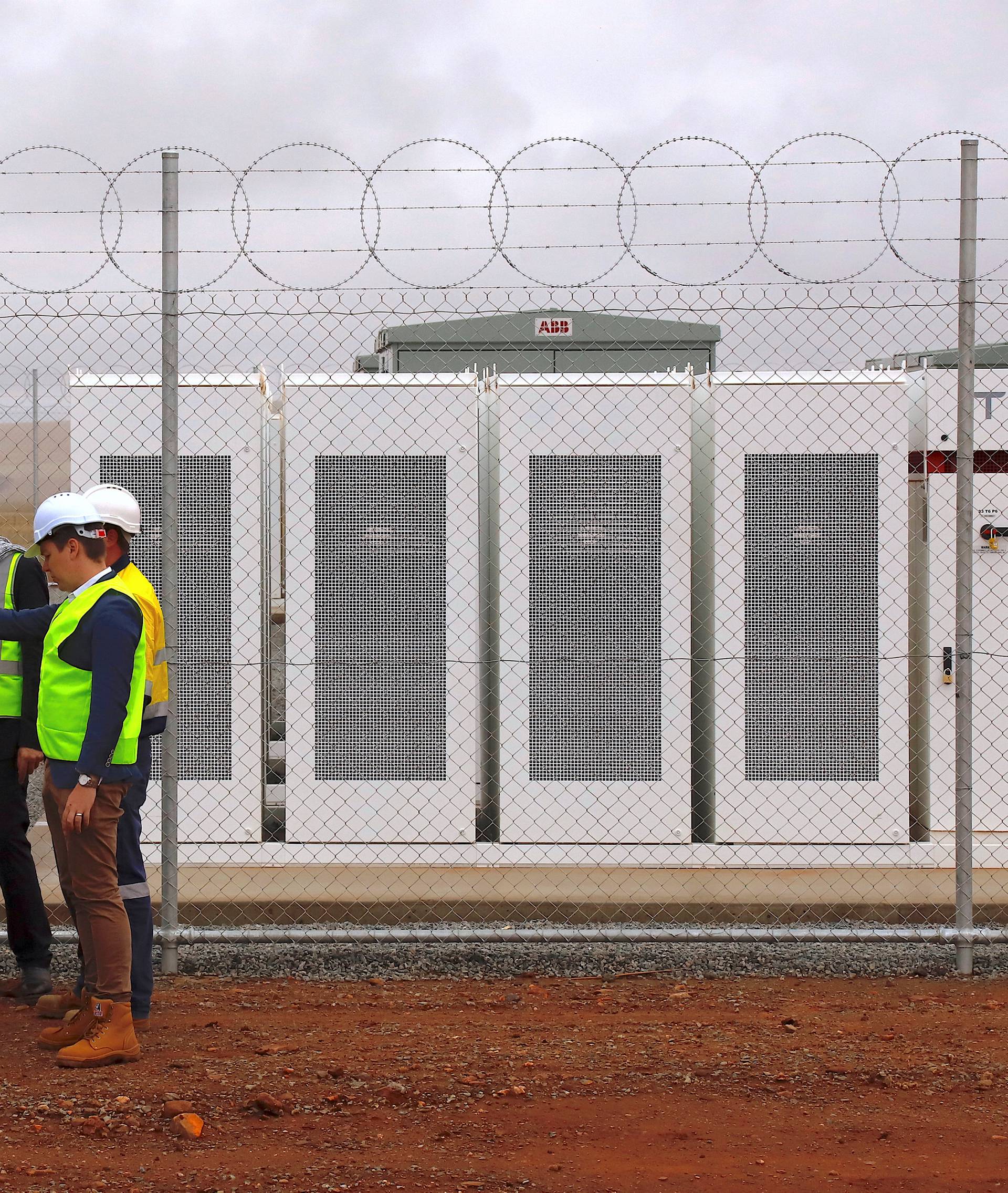 Officials and workers gather outside the compound housing the Hornsdale Power Reserve, featuring the world's largest lithium ion battery made by Tesla, during the official launch near the South Australian town of Jamestown