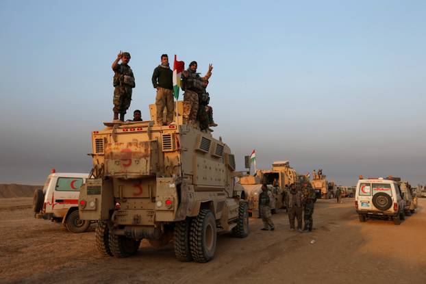 Peshmerga forces stand on a military vehicle in the town of Bashiqa