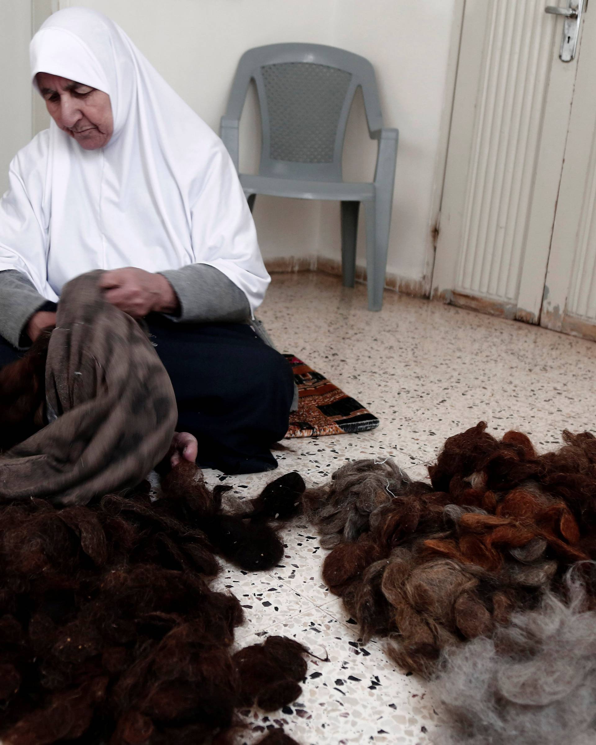 Ezzeya Daraghmeh, an 82-year-old Palestinian woman who said she has kept parts of her hair she cut over 67 years, stuffs a pillow with her hair in the West Bank town of Tubas