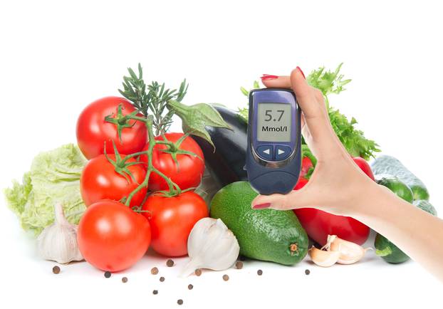 Diabetes concept glucose meter in hand and healthy organic food 