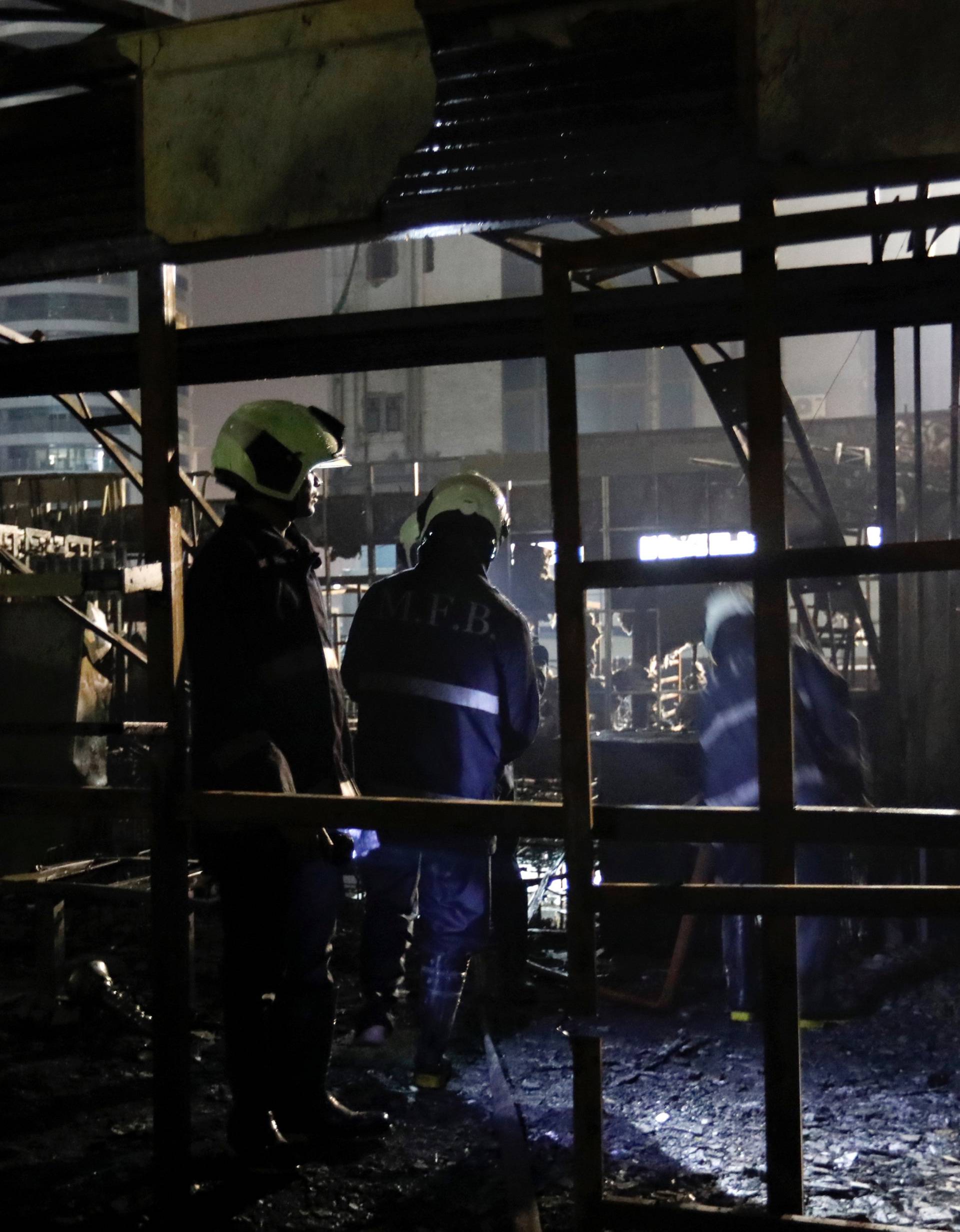 Firemen inspect the debris after a fire at a restaurant in Mumbai