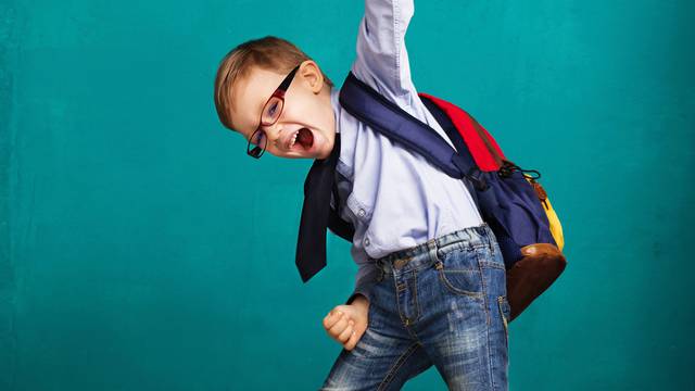 smiling little boy with big backpack jumping and having fun