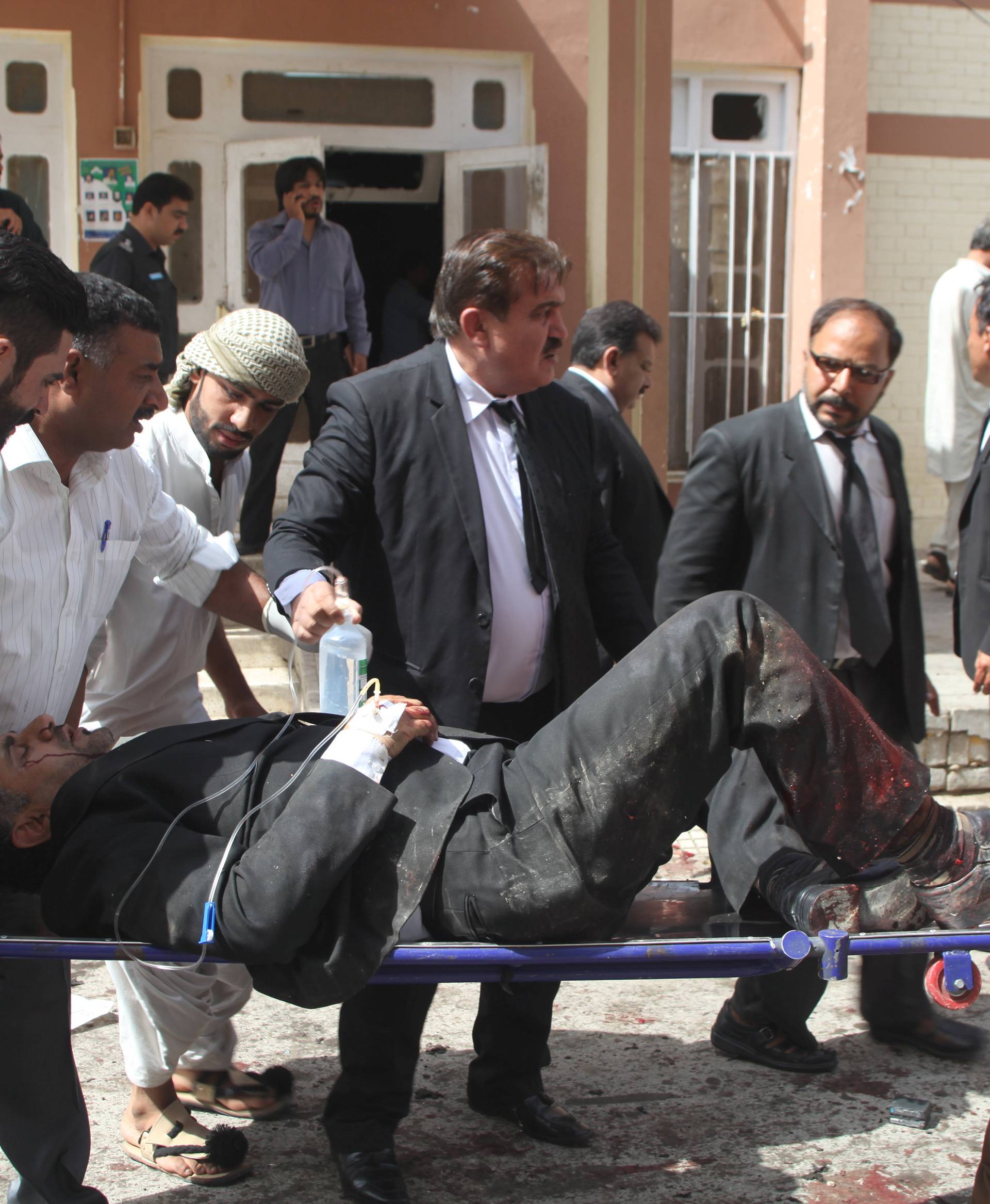 First responders and volunteers transport an injured man away from the scene of a bomb blast outside a hospital in Quetta