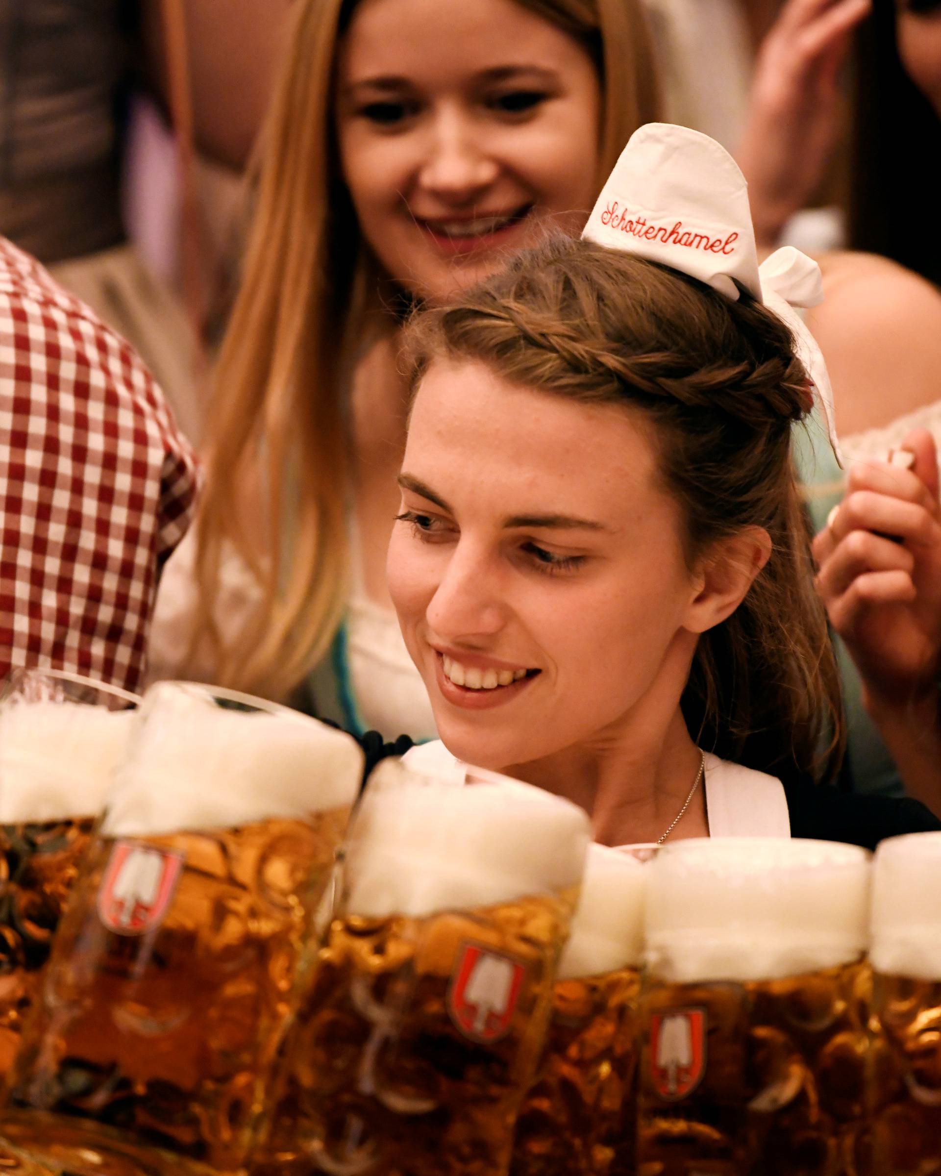 A waitress carries mugs of beer during the opening day of the 185th Oktoberfest in Munich