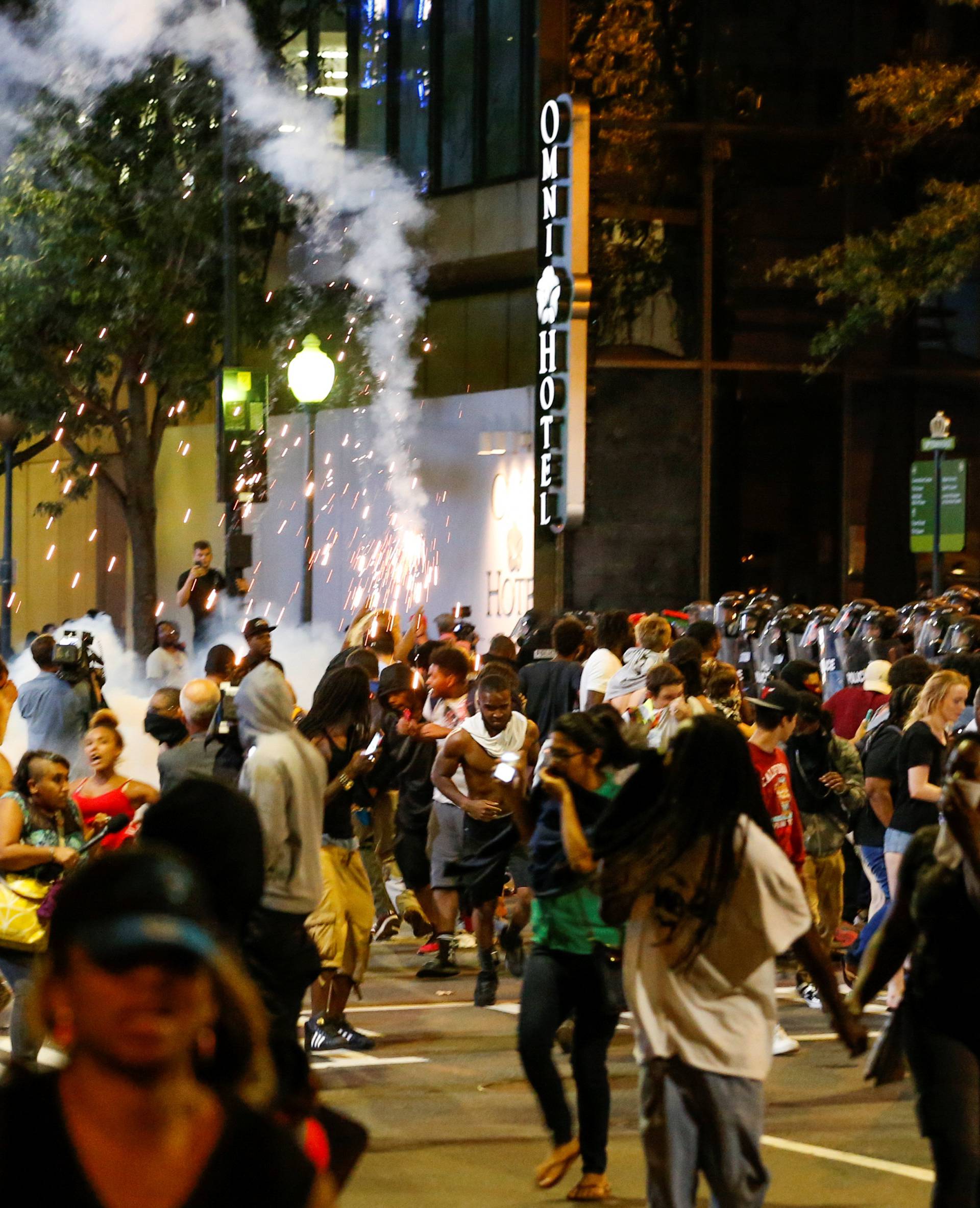 People run from flash-bang grenades in uptown Charlotte, NC during a protest of the police shooting of Keith Scott, in Charlotte