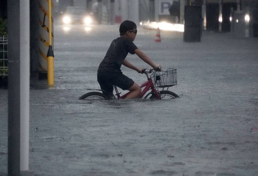 A boy cycles through a flooded street as Typhoon Dujuan brings heavy rain, in Ichikawa