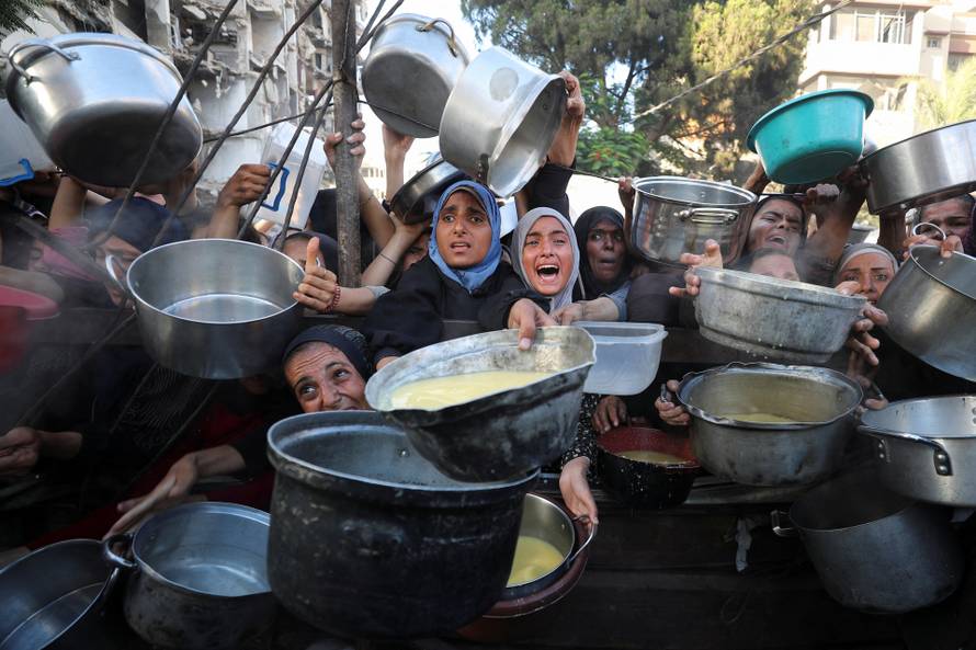 Palestinians wait to receive food from a charity kitchen, amid a hunger crisis, in Gaza City