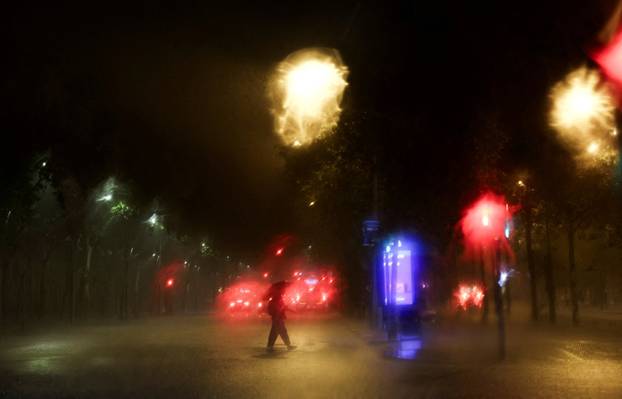 A person crosses Gran Via street during a heavy rain in Barcelona