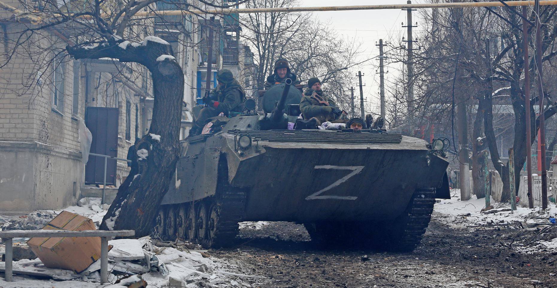 Service members of pro-Russian troops drive an armoured vehicle in a residential area in Volnovakha