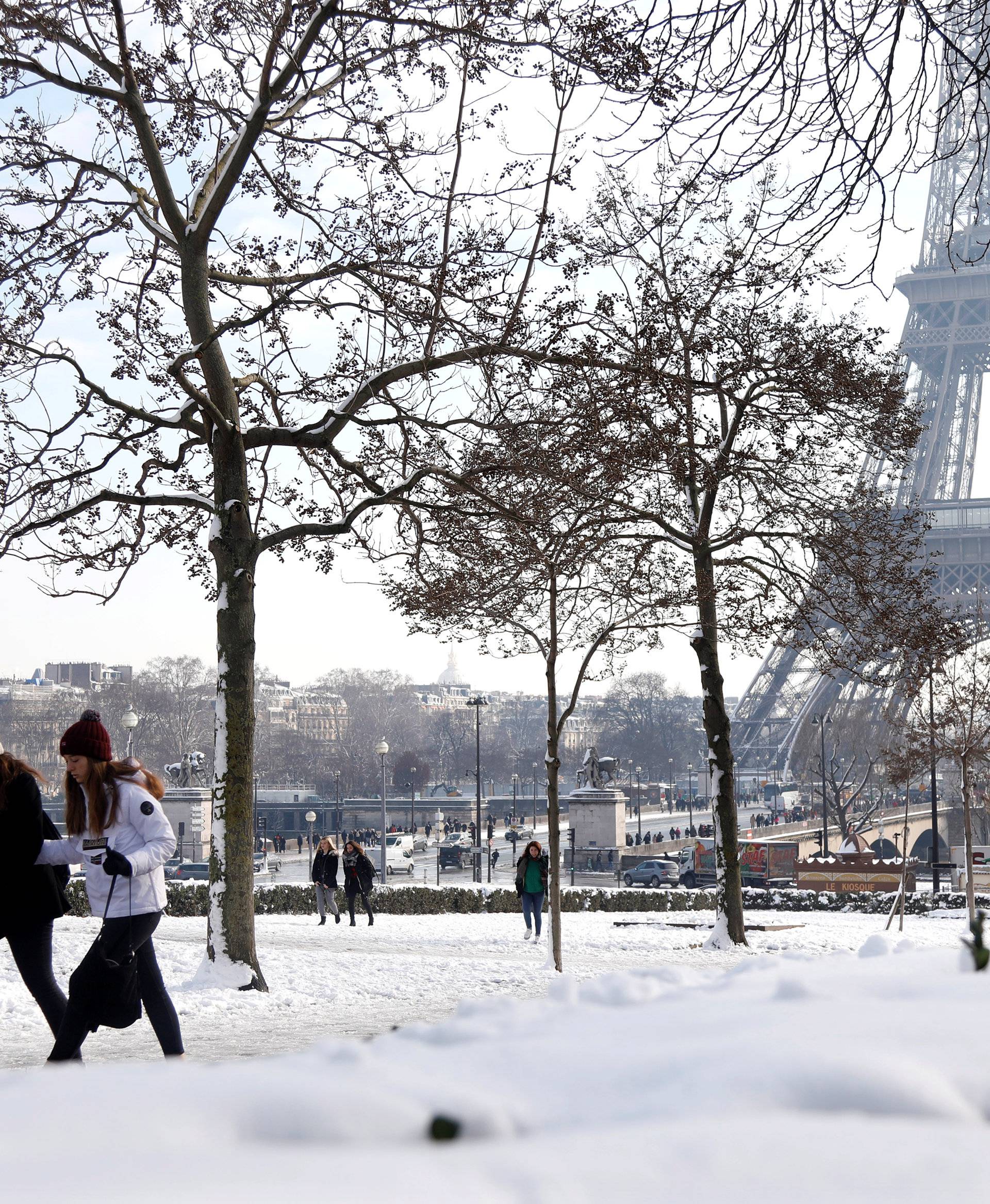 People walk on the snow-covered Trocadero gardens near the Eiffel Tower in Paris, as winter weather with snow and freezing temperatures arrive in France