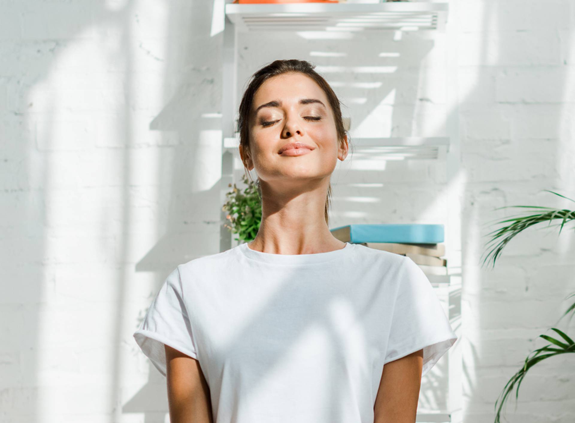 beautiful happy girl with closed eyes practicing yoga in lotus position in bedroom in the morning