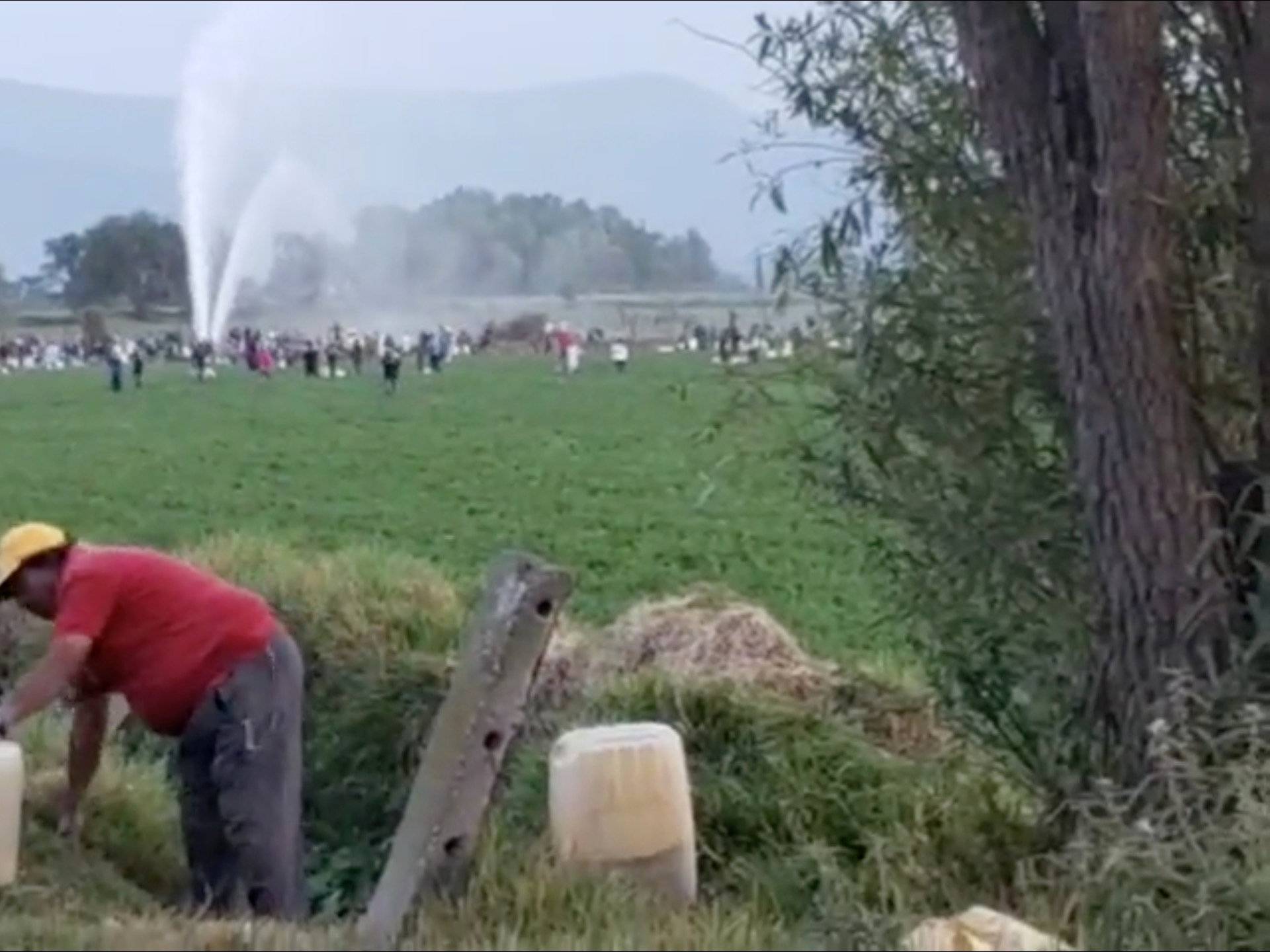 People gather at the site of a ruptured pipeline in the municipality of Tlahuelilpan, in Hidalgo