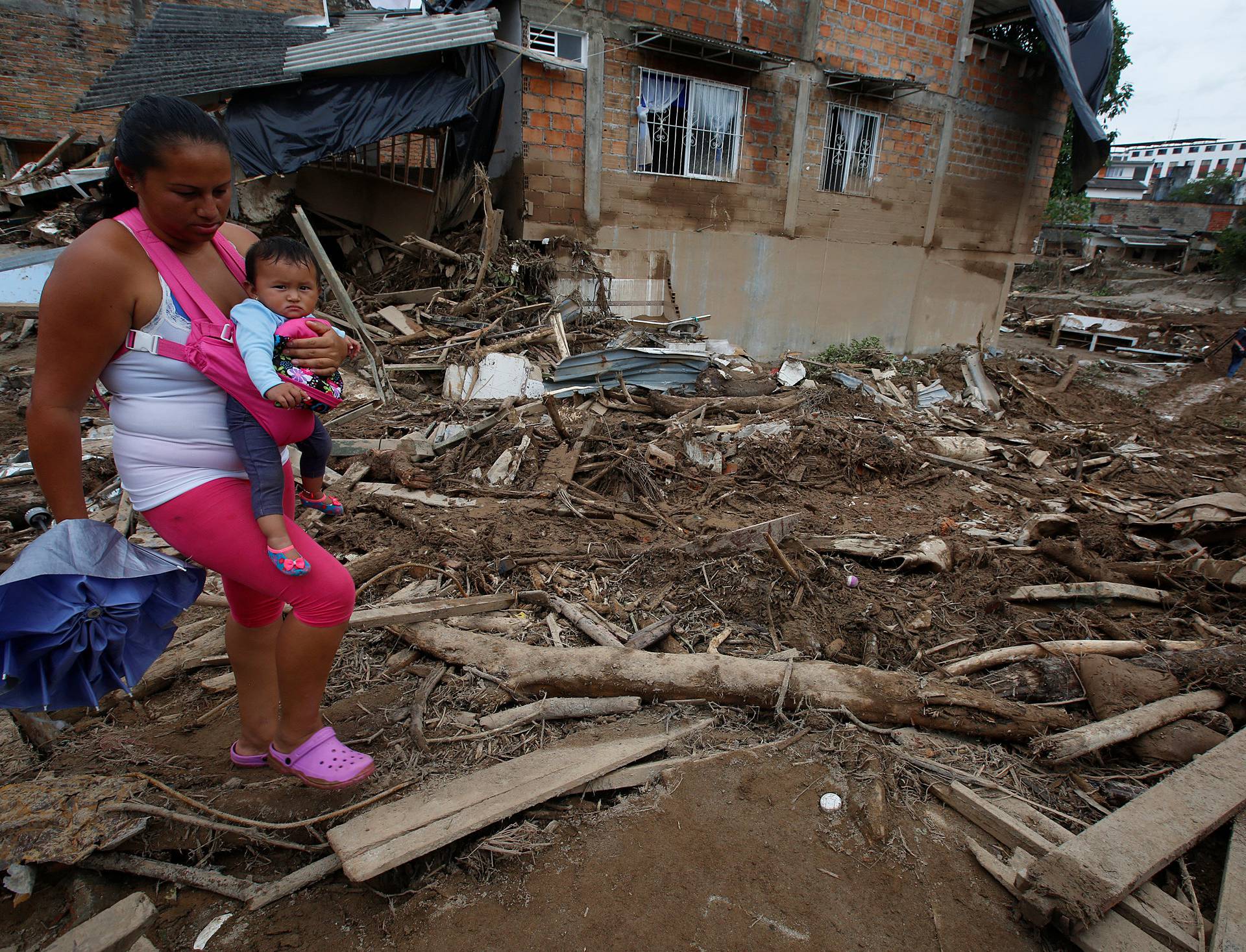 A woman walks with her daughter on a street destroyed after flooding and mudslides caused by heavy rains leading several rivers to overflow, pushing sediment and rocks into buildings and roads, in Mocoa