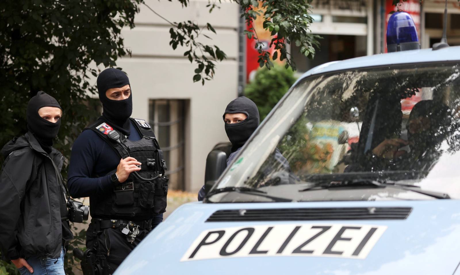 Police officers gather outside during a raid in an apartment building at Kreuzberg district in Berlin