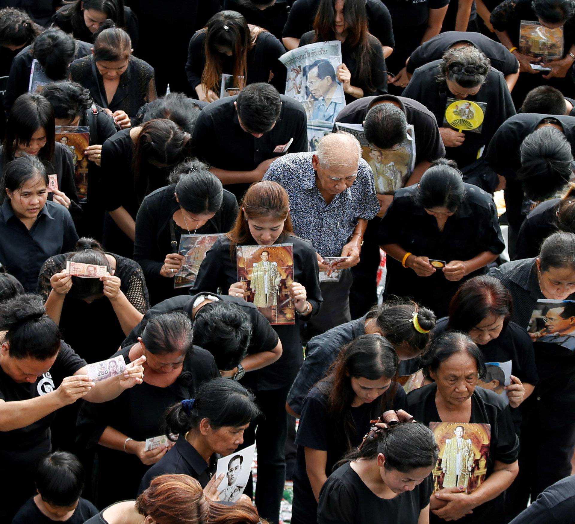 Mourners bow as they gather outside of the Grand Palace to sing for a recording of the royal anthem in honour of Thailand's late King Bhumibol Adulyadej, in Bangkok