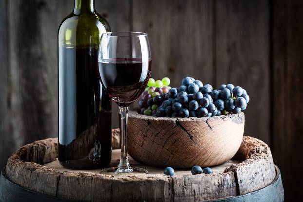 Intensive red wine with sweet grapes on wooden barrel