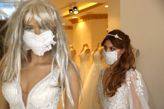 An employee presents a wedding dress with a mask at the Mezopotamya bridal gowns shop in Diyarbakir