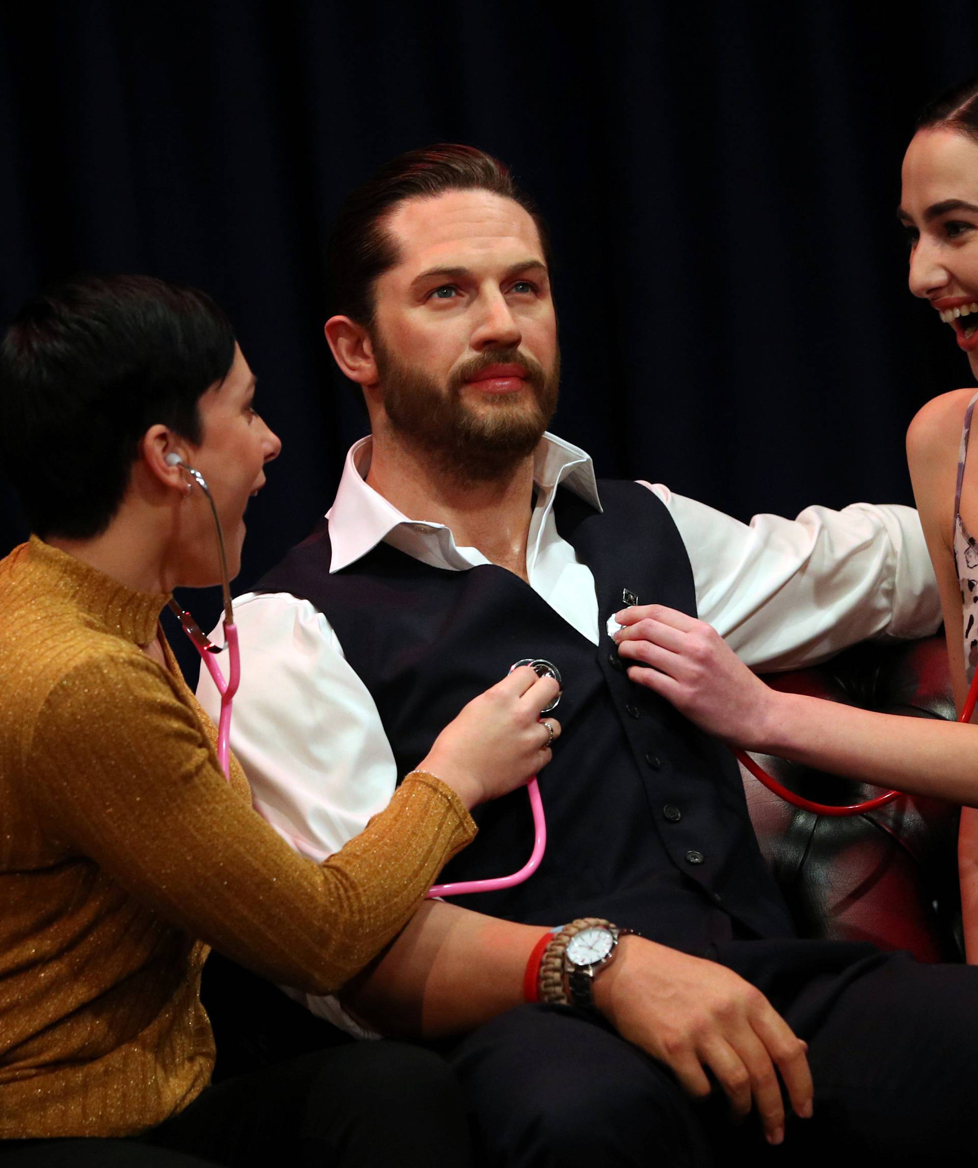 People pose next to Madame Tussauds' wax figure of British actor Tom Hardy which has a soft warm chest and a beating heart, in London