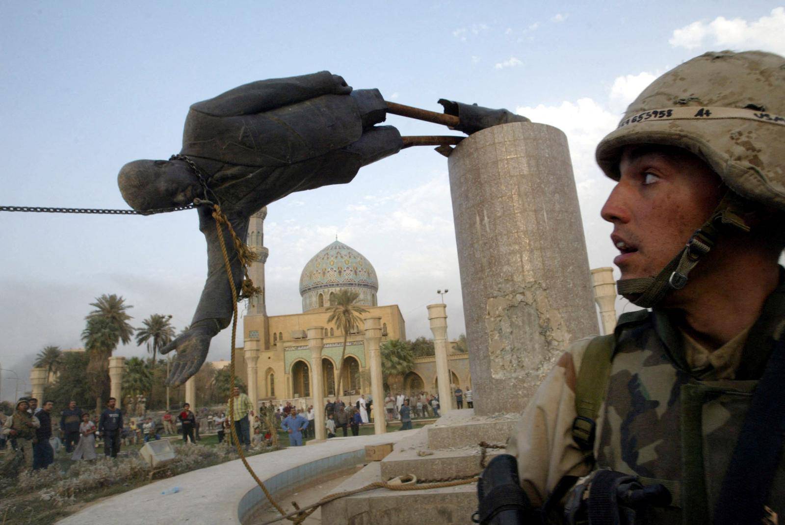 FILE PHOTO: A U.S. soldier watches a statue of President Saddam Hussein fall in Central Baghdad