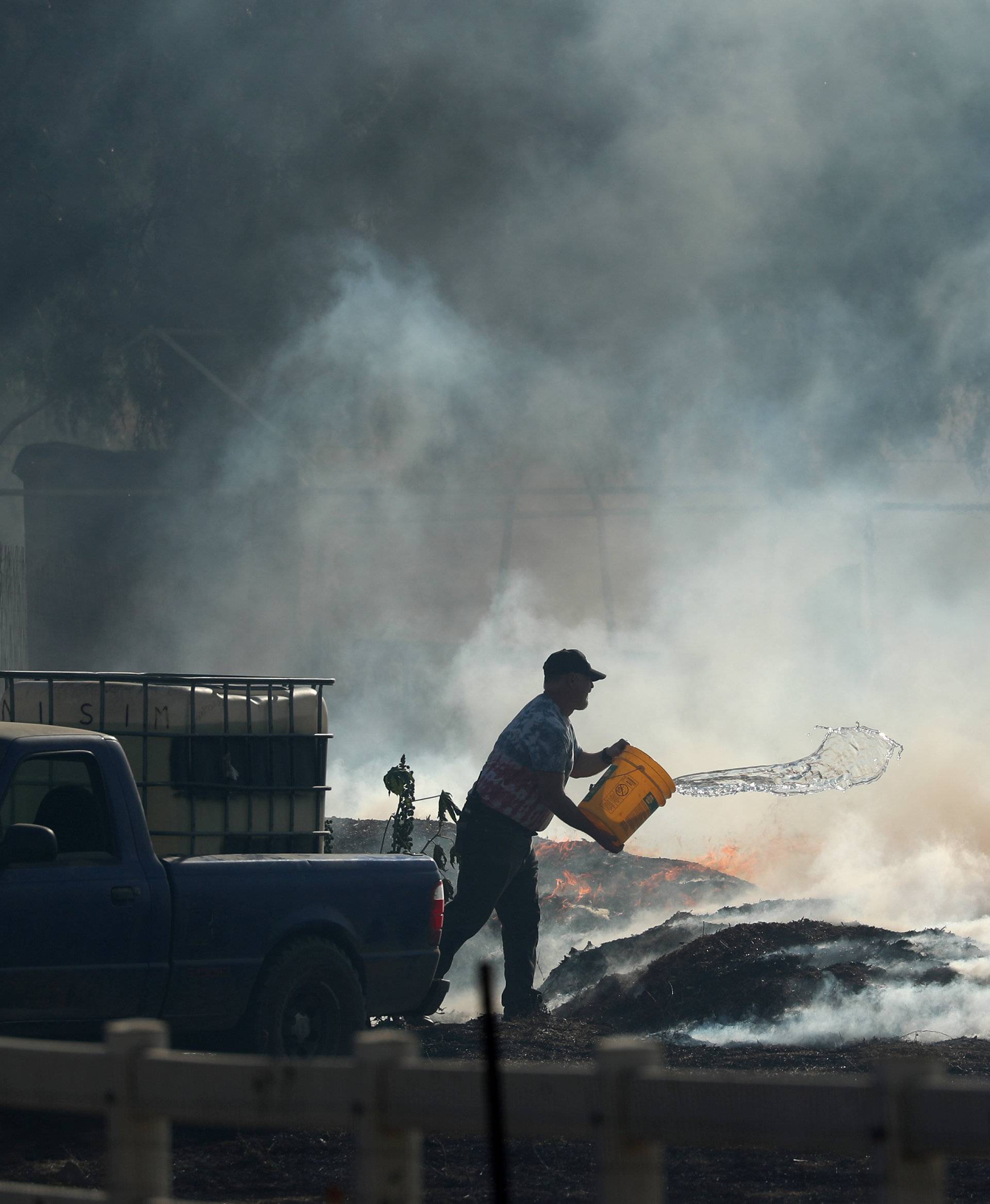 A rancher does what he can to try and put out flames after the Lilac Fire, a fast moving wild fire, came through Bonsall, California