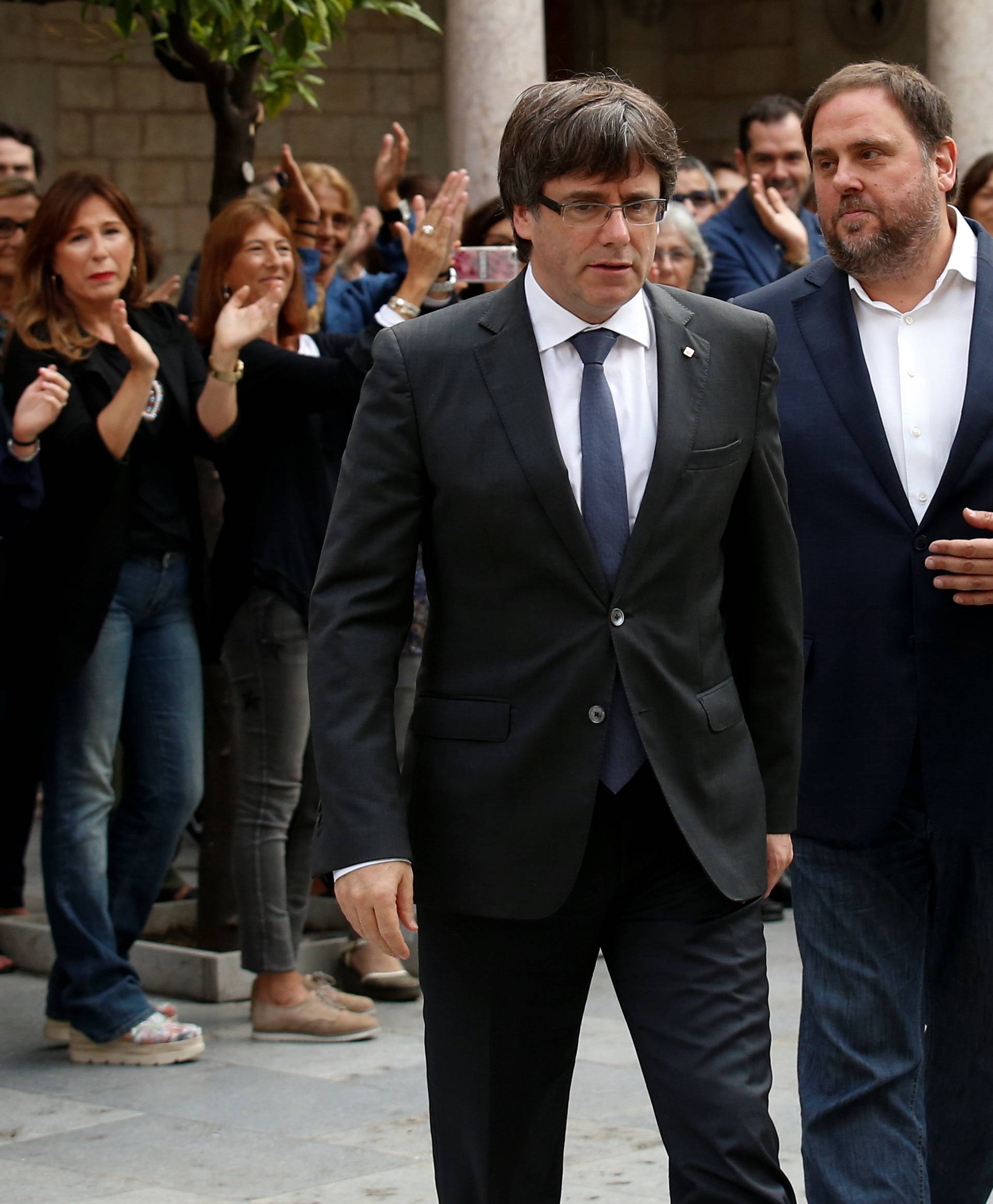 Catalan President Puigdemont and Vice President Junqueras are applauded by employees upon arriving to an extraordinary cabinet meeting in Barcelona
