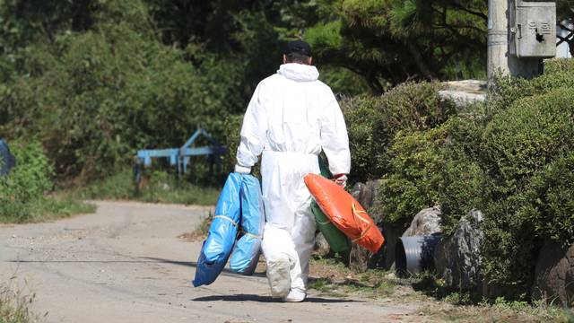 A quarantine official wearing protective gear walks near a pig farm involved in African swine fever in Yeoncheon