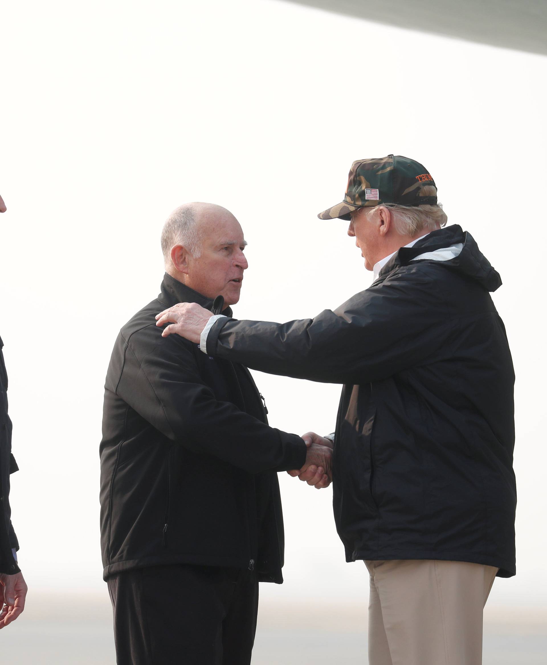 President Donald Trump shakes hands with Governor Jerry Brown as Governor-elect Gavin Newsom looks on upon arriving at Beale Air Force Base California