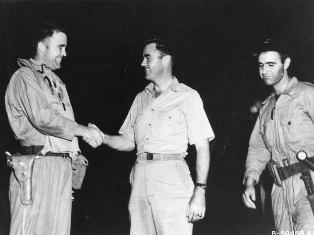 Major Charles W. Sweeney (left), pilot of the B-29 BOCKSCAR which dropped the atomic bomb on Nagasaki on August 9, 1945, is shown before his mission shaking hands with Col Paul W. Tibbets, pilot of ENOLA GAY which atom bombed Hiroshima on 6 August 1945. M