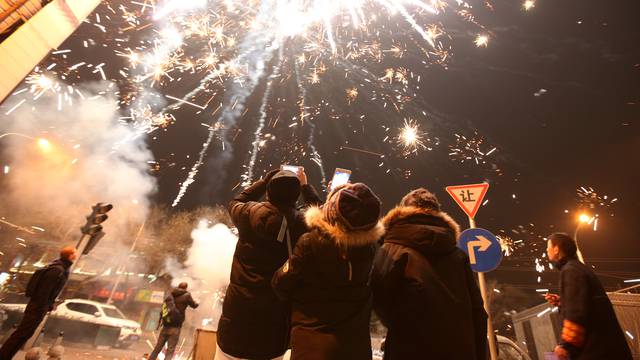 People watch fireworks explode on the eve of the Spring Festival, in Beijing