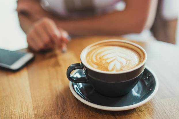 Tasty cappuccino in cup on wooden table