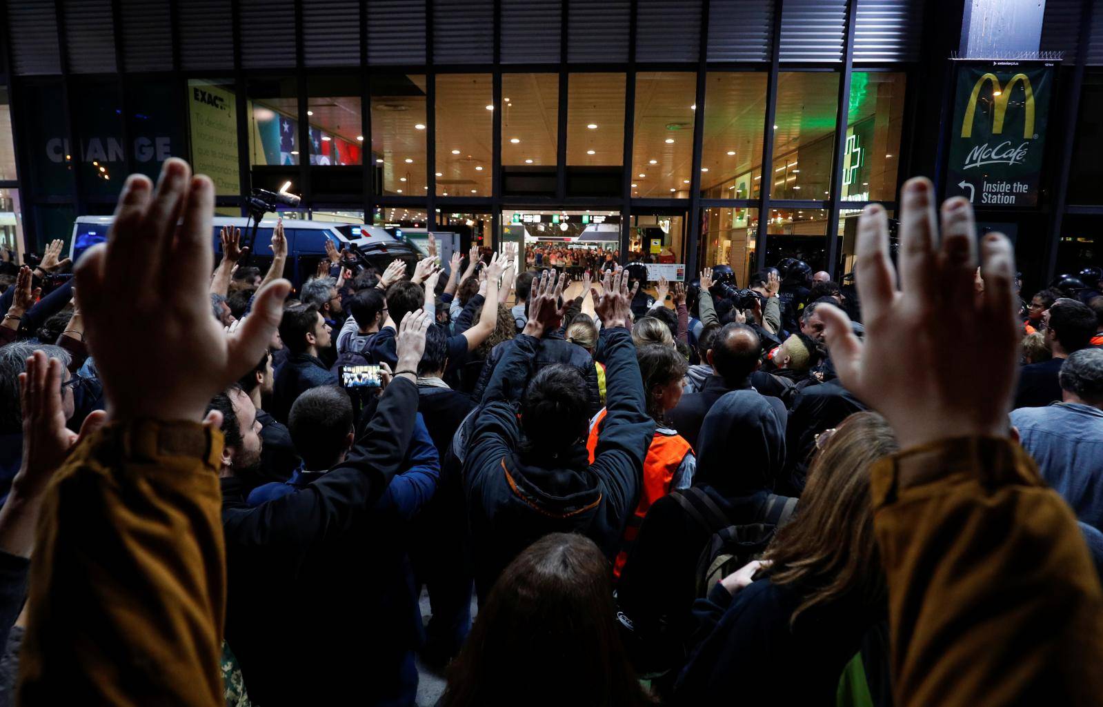 People raise their hands as they participate in a protest outside the Sants train station in Barcelona